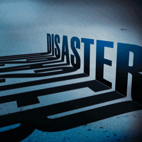 The word "disaster" casts a long shadow on a blue-gray surface, emphasizing the concept visually through shadow and light.