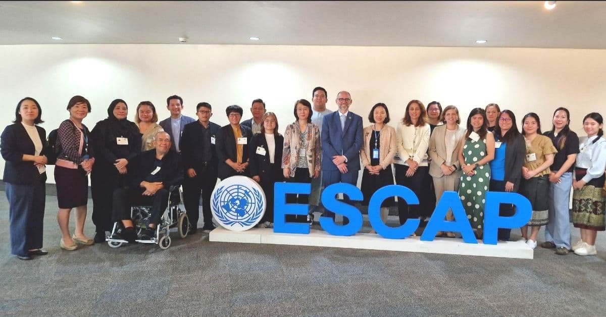 Group of people standing behind a large "ESCAP" sign, with a UN logo on display.