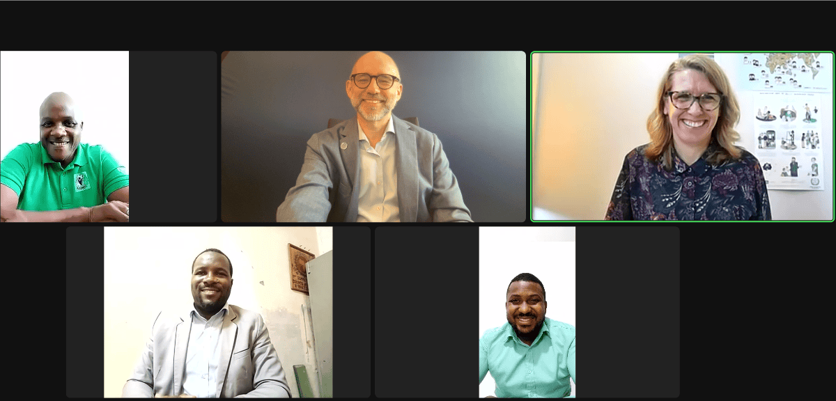 A virtual meeting with five participants smiling on a video call, each in individual frames.