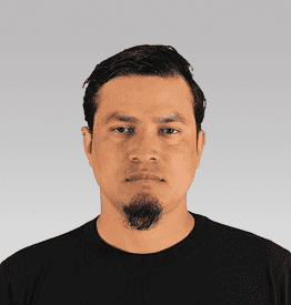 Man with short hair and a goatee wearing a black shirt, against a light gray background.