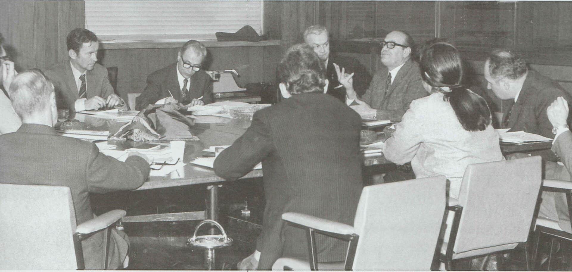 A group of people sitting around a large conference table for a meeting.