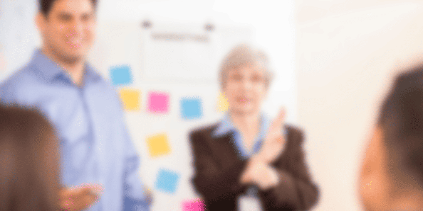 Blurry image of two people near a whiteboard with colorful sticky notes.
