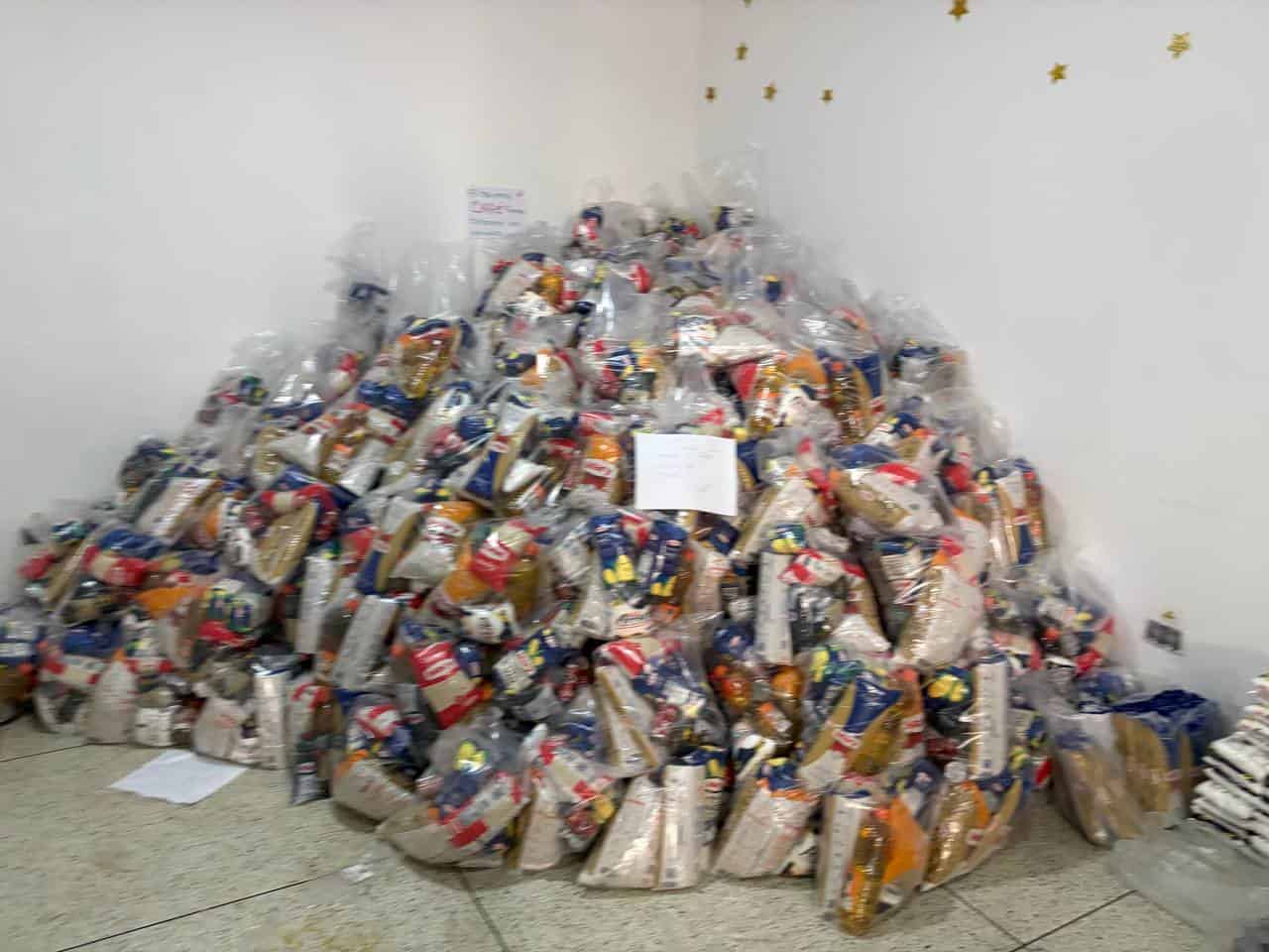 A large pile of clear plastic bags filled with assorted food items is stacked against a wall in a room with star decorations.