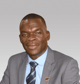 A person in a gray suit and blue tie smiling against a gray background.