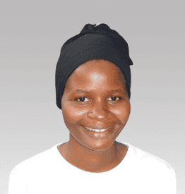 A person wearing a black headscarf and a white shirt smiles at the camera against a gray background.