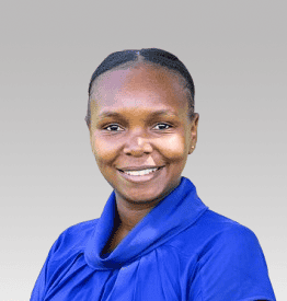 A woman wearing a blue top smiles at the camera against a light grey background.