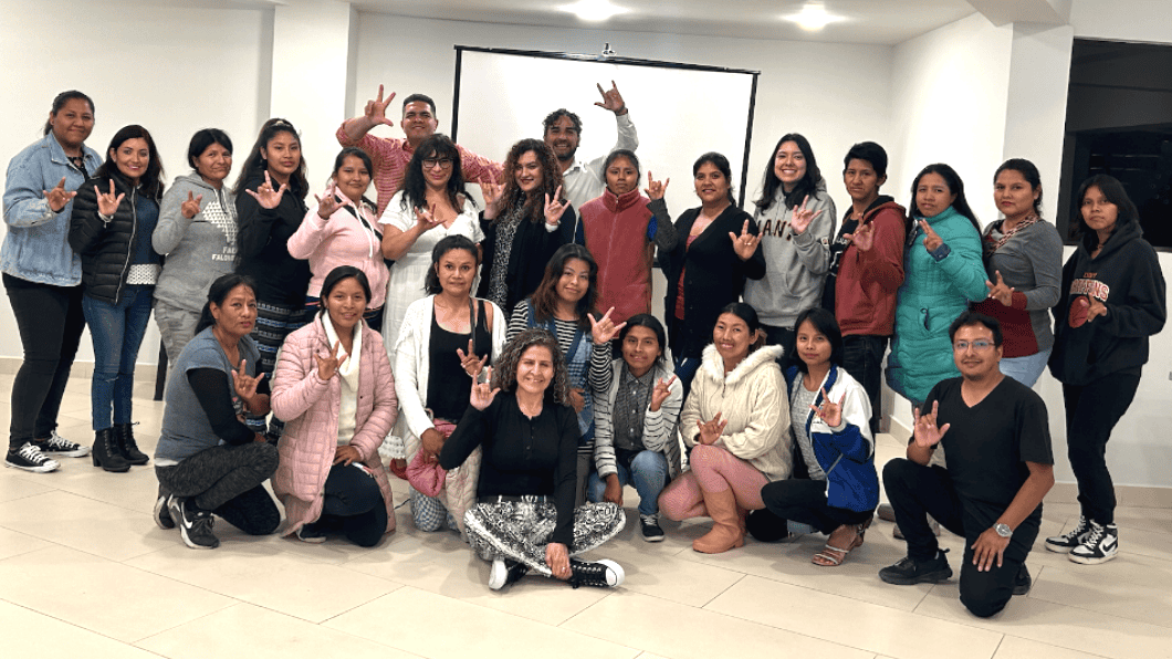 A group of people posing indoors, making hand gestures and smiling at the camera.