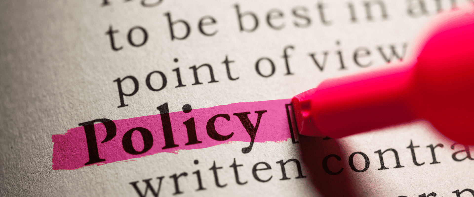 The word "Policy" is highlighted in pink on a printed page, with a pink highlighter partially visible.